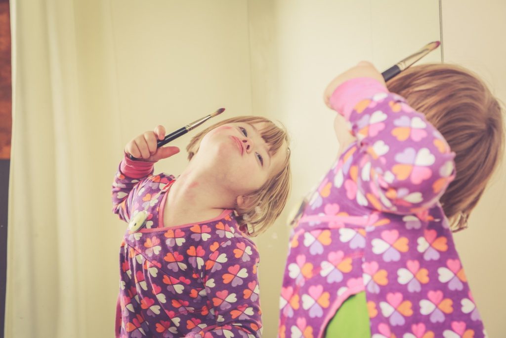 Un petite fille devant un miroir. jeu pour développer les neurones miroirs
